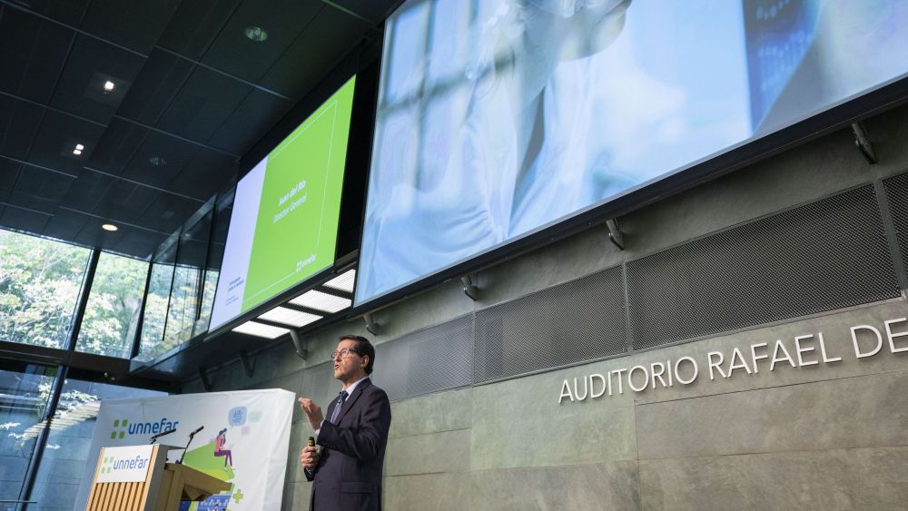 Juan Del Río, director general y ponente de Grupo Unnefar presentando los resultados de 2020 en el Auditorio Rafael del Pino, con pantallas proyectando la presentación.