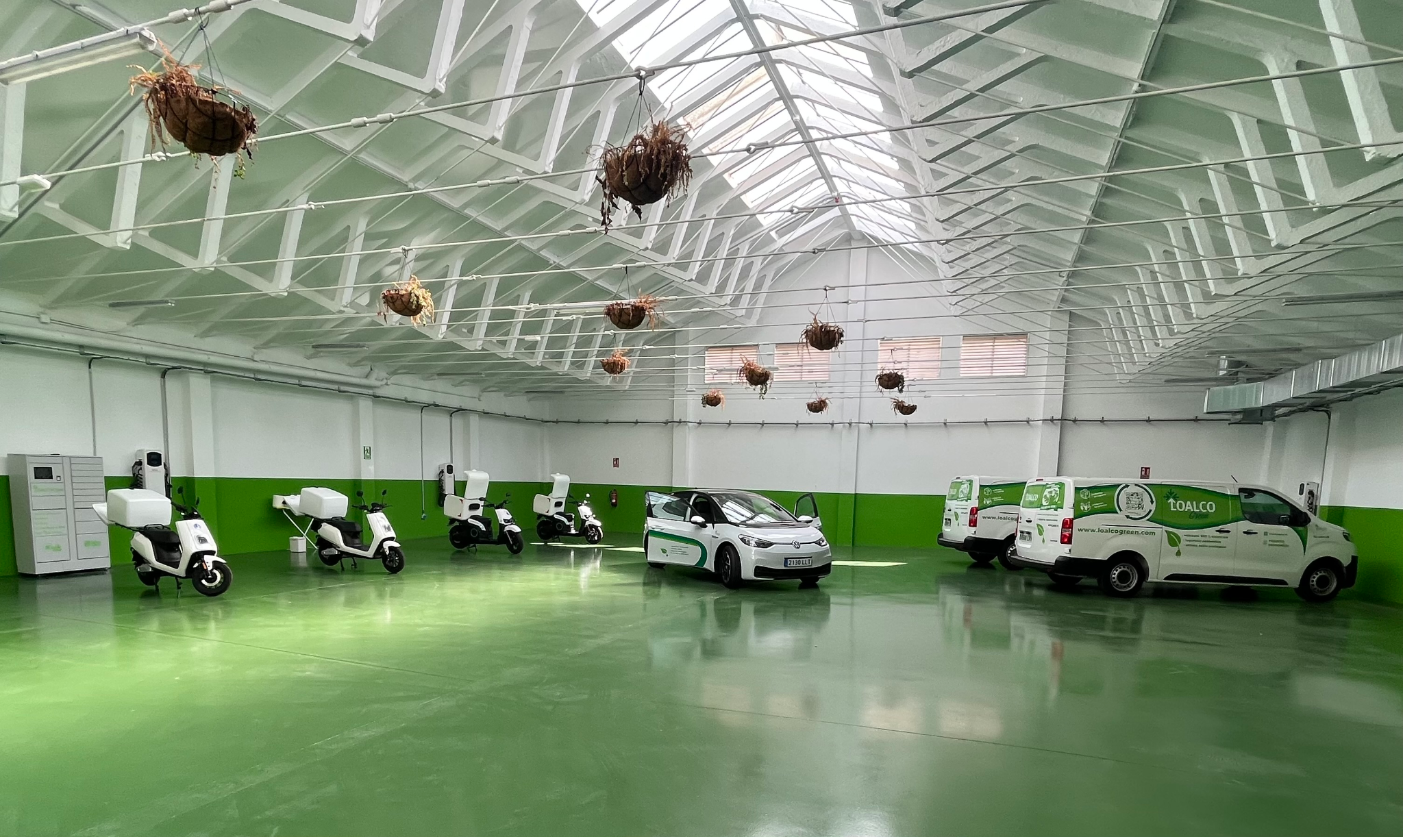 Interior del centro logístico de movilidad sostenible con scooters eléctricos IoT y vehículos de reparto de Loalco Green y Novaltia, utilizados para la distribución farmacéutica inteligente y de bajas emisiones.
