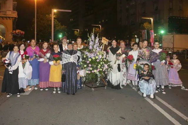 Grupo de participantes de Novaltia en la Ofrenda de Flores a la Virgen del Pilar con trajes tradicionales y ramos de flores.